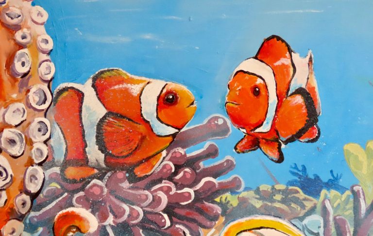 Großes Unterwasser-Graffiti mit orangefarbenem Clownfischen, Fischen und Korallen im Innenhof des Mad Monkeys Waterfront Hostels in Cairns
